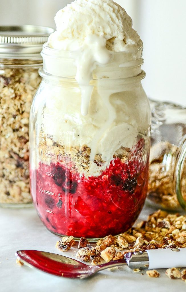 berry compote with crisp crumbles and vanilla ice cream in a mason jar