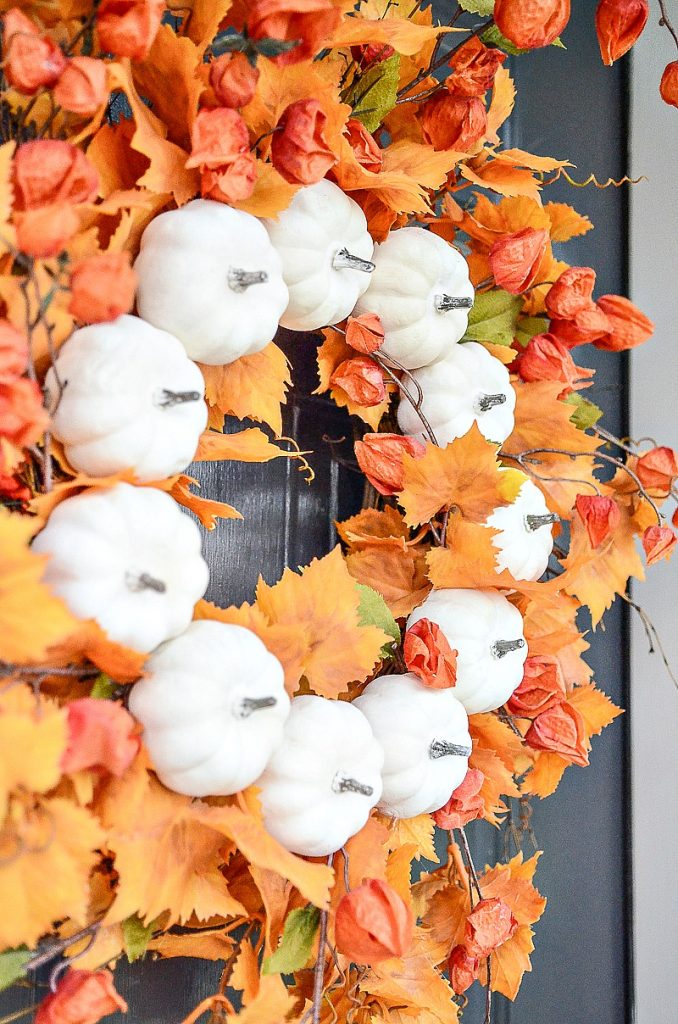 gorgeous orange leaves and Chinese lanterns on a fall wreath with little white pumpkins