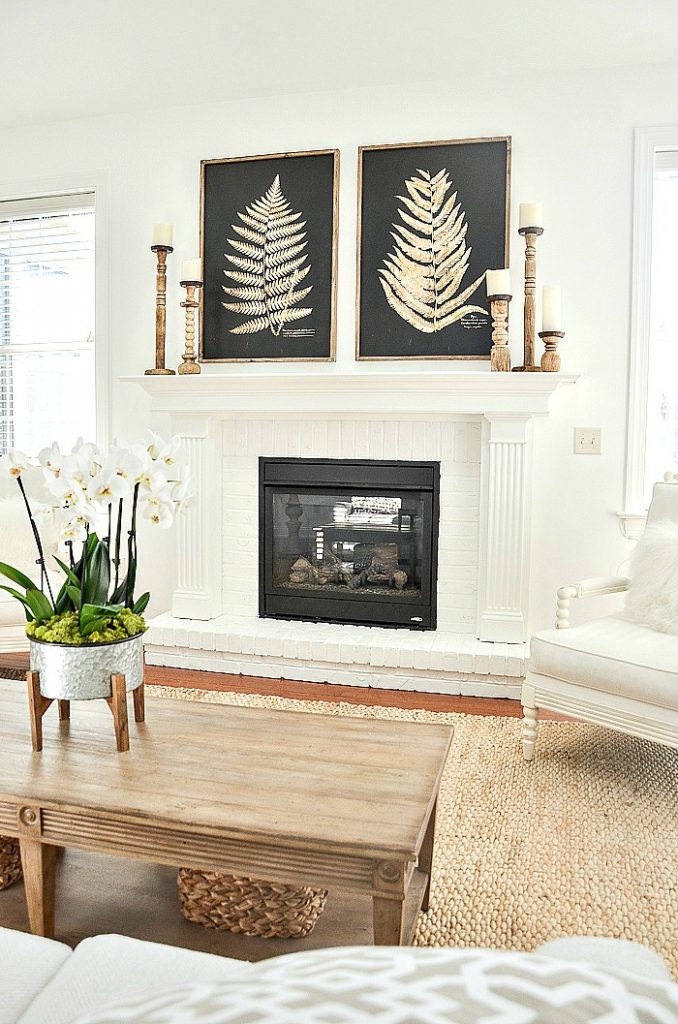 dramatic huge black pictures with blond colored ferns over a white fireplace