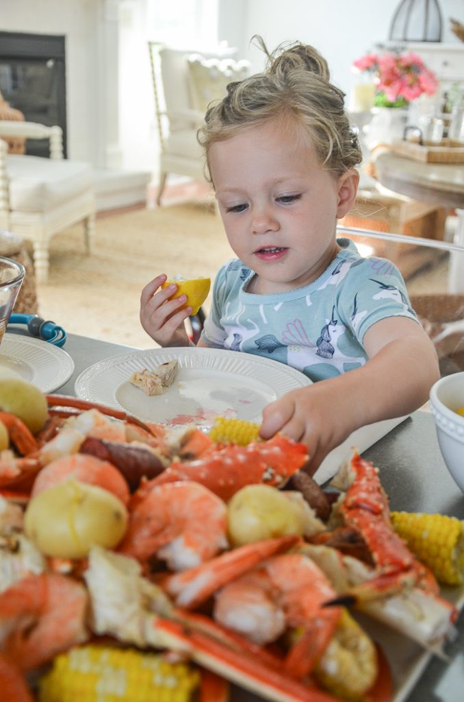A LITTLE GIRL EATING HER FIRST LOW COUNTRY BOIL. PICKING UP A PIECE OF CORN