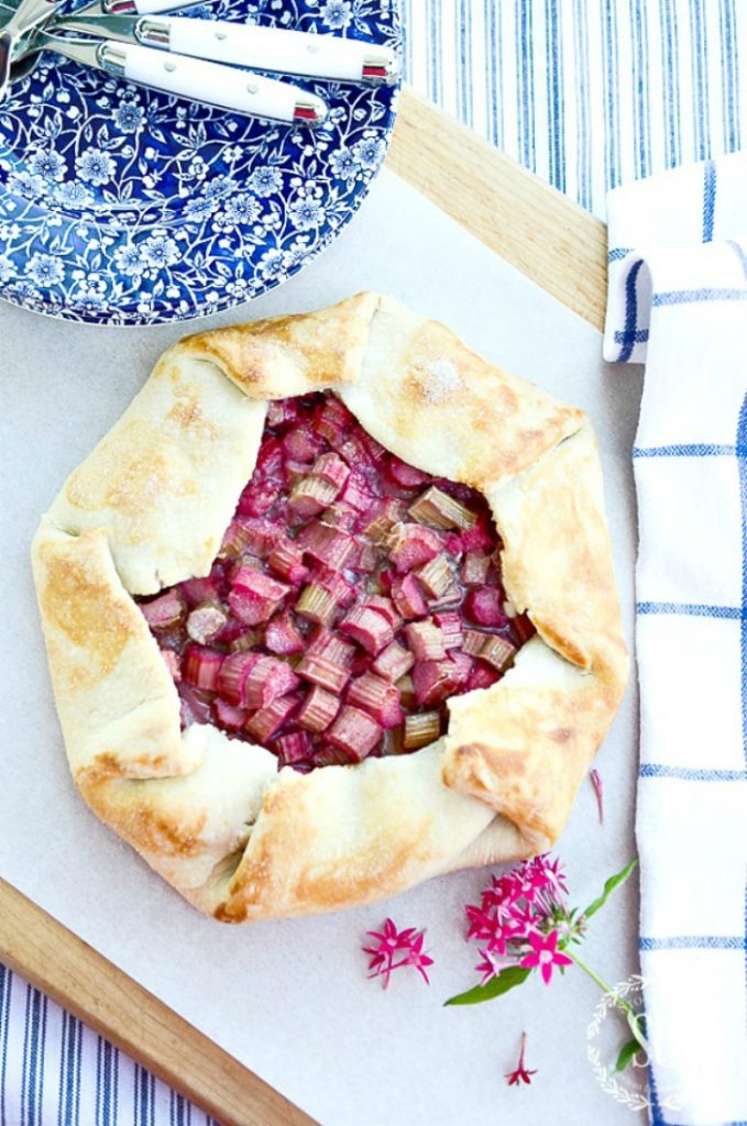 rhubarb galette on a work surface with blue and white dishes and a hot pink flower