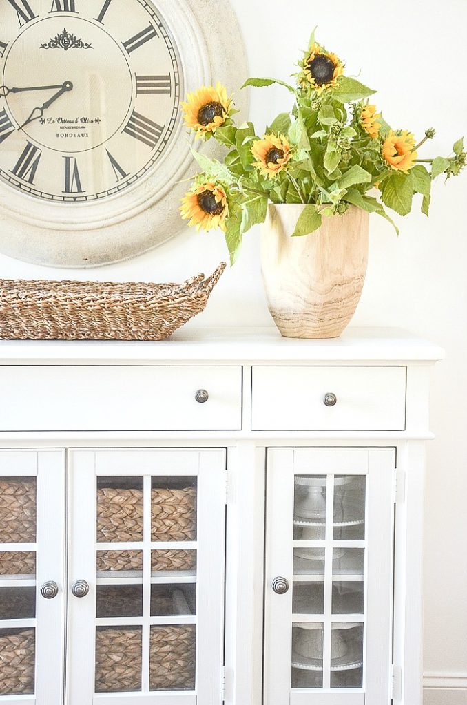 A tall wooden vase filled with sunflowers for a summer home tour