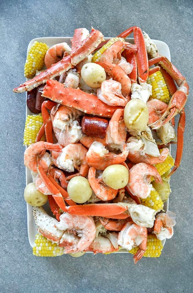 A WHITE PLATTER OF LOW COUNTRY BOIL ON A GRAY CONCRETE TABLE