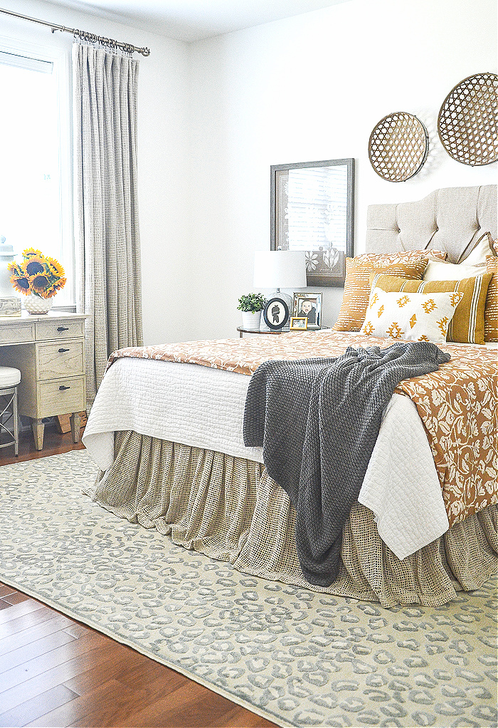 A BED WITH A WHITE COVERLET AND GOLD DUVET COVER AND MATCHING THROW PILLOWS.