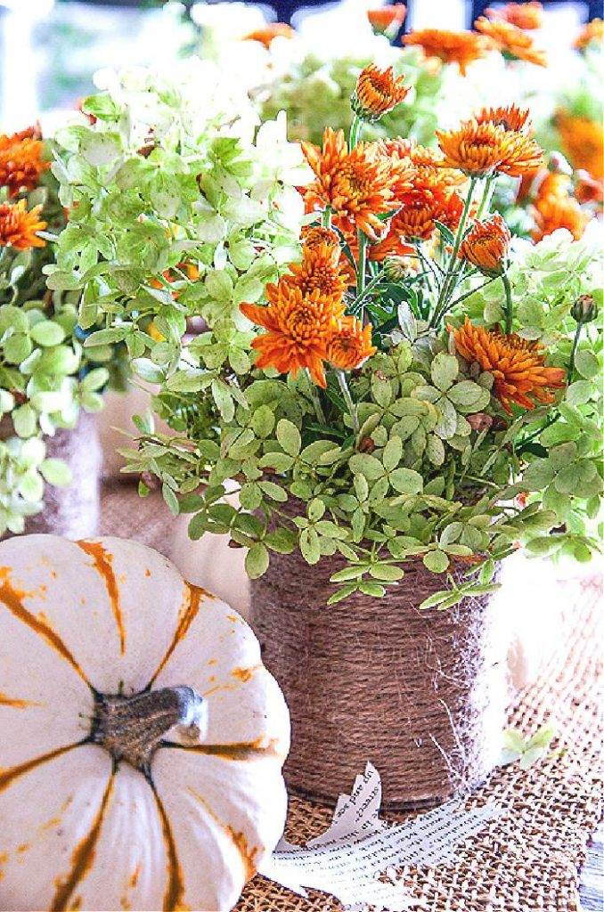 TWINE WRAPPED CONTAINERS WITH FALL FLOWERS IN THEM NEXT TO A PUMPKIN