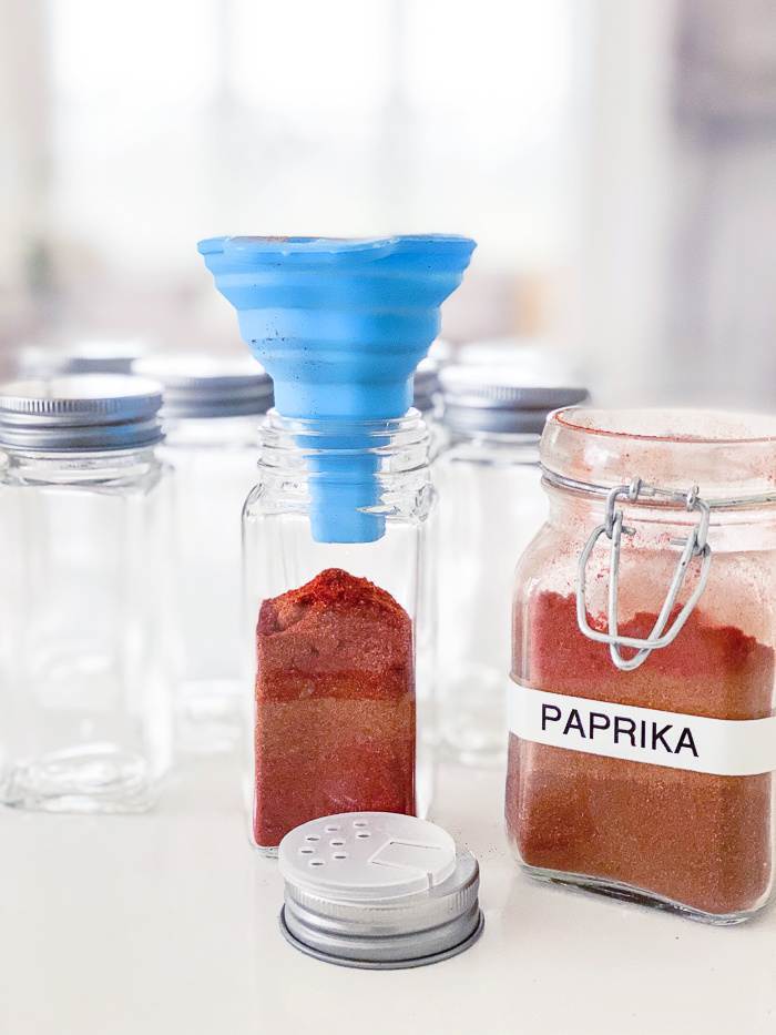 PAPRIKA BEING FUNNELED INTO A SPICE JAR
