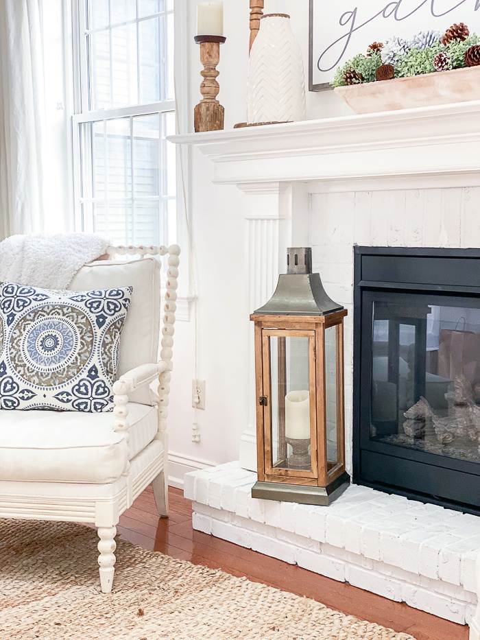 WARM WHITE FIREPLACE AND CHAIR WITH A BLUE PILLOW ON IT