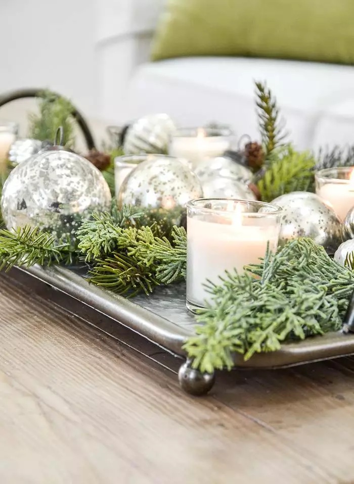 greens, candles and metallic Christmas balls on a metal tray