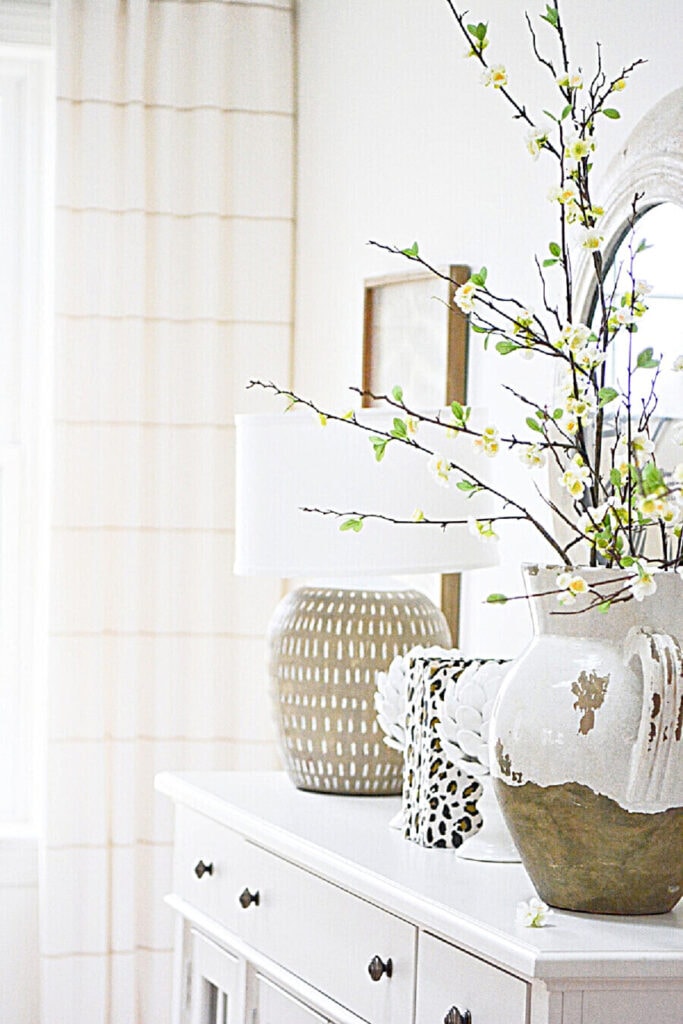 SPRING DECOR IDEAS- Faux spring blooming branches in a big urn on a white buffet.