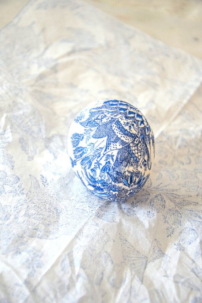 ONE PRETTY DECOUPAGED CHINOISERIE EGG ON A DECORATIVE BLUE AND WHITE NAPKIN