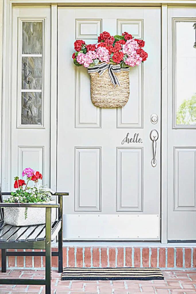 FRONT PORCH WITH A BASKET OF GERANIUMS ON THE FRONT DOOR