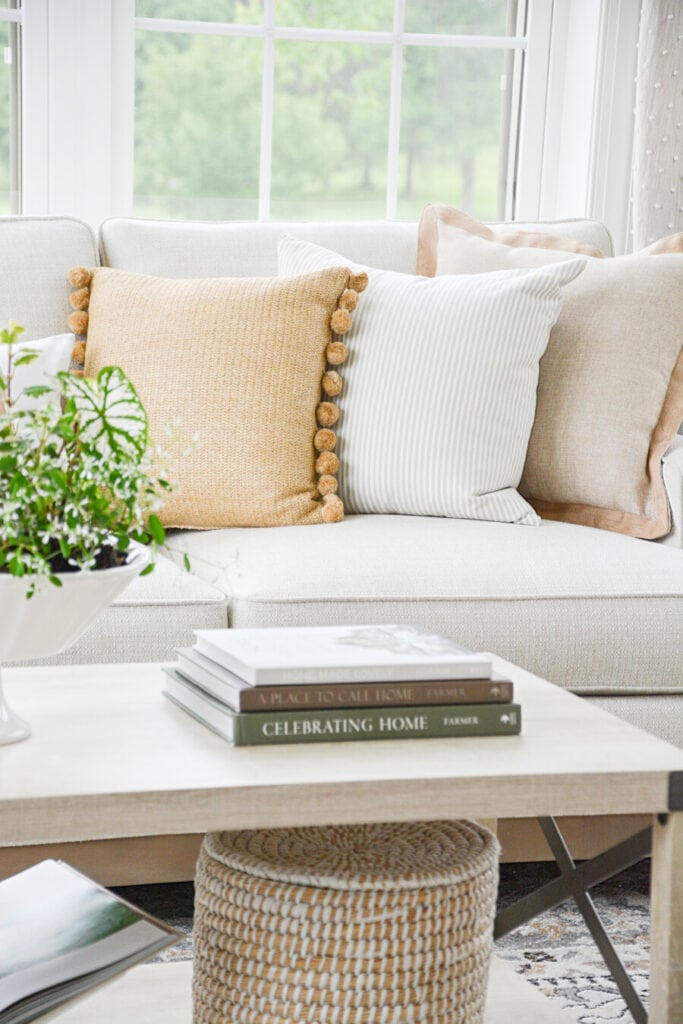 THREE DIFFERENT COLORED NEUTRAL PILLOWS ON A NEUTRAL SOFA