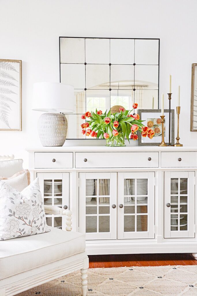 living room with a vase of white tulips on a buffet