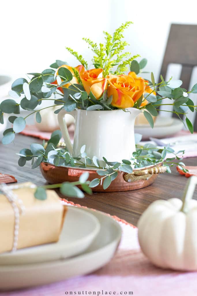 orange roses in a white pitcher on a set table