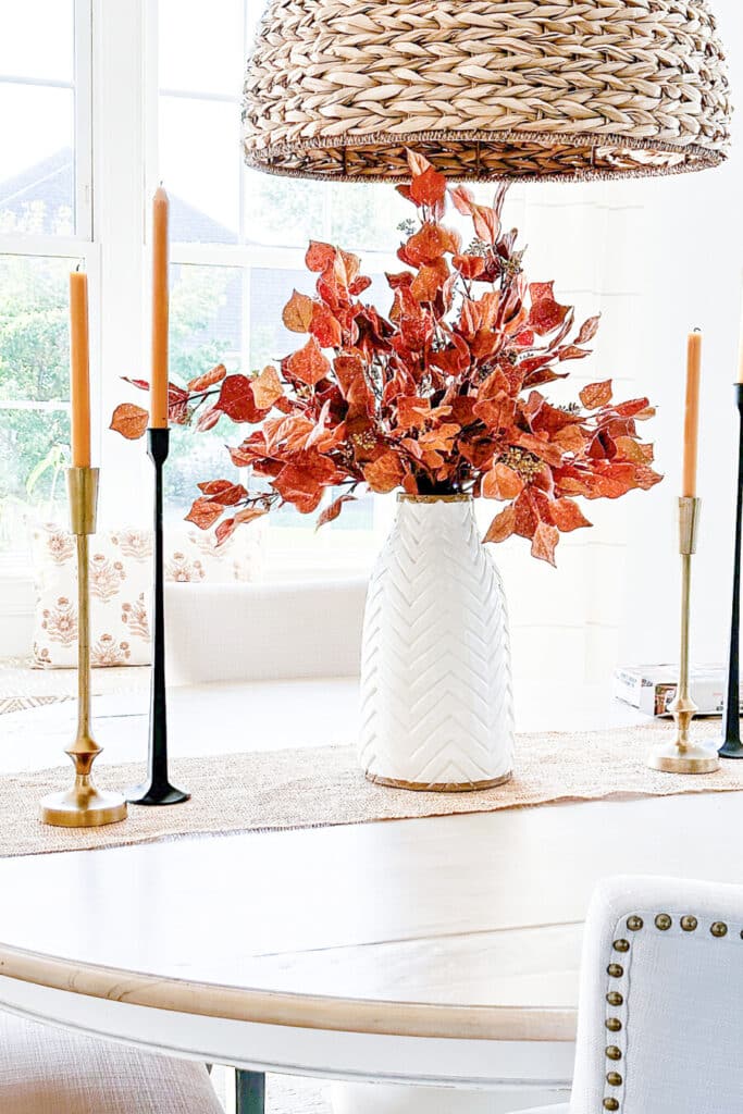 white vase filled with faux fall leaves
