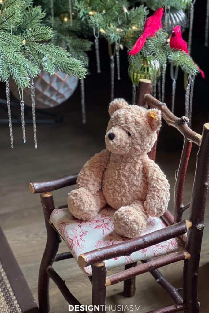 teddy bear sitting in a stick chair under a tree