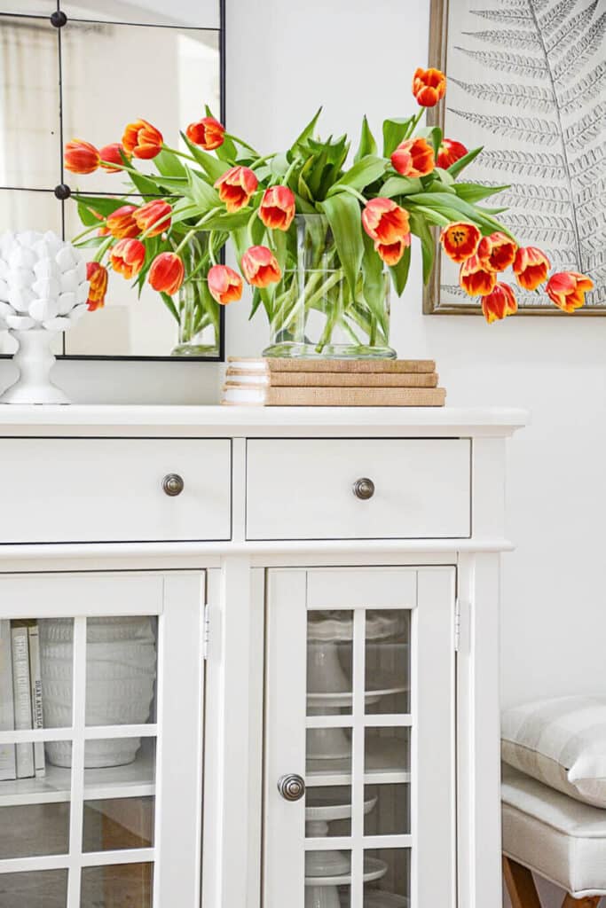 DECORATING WITH BOOKS-books with a vase of tulips on top of it