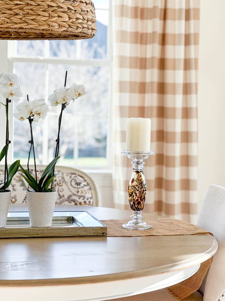 orchids on a dining room table with a tall candle