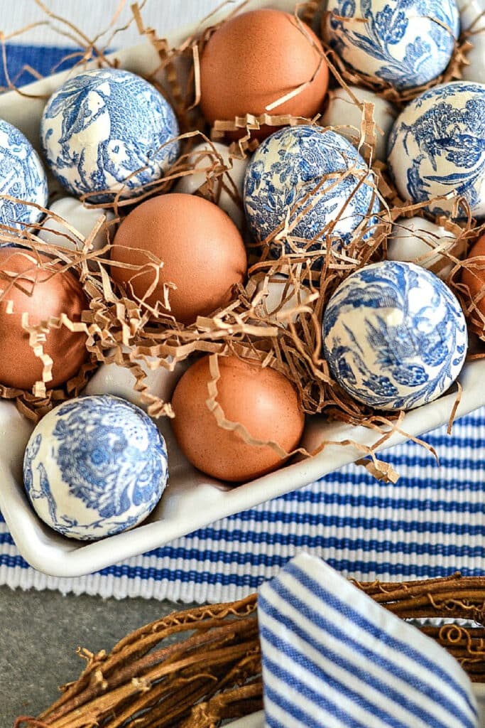 onion skinned dyed Eggs and Chinoiserie Eggs in a white ceramic egg carton with brown crinkle paper