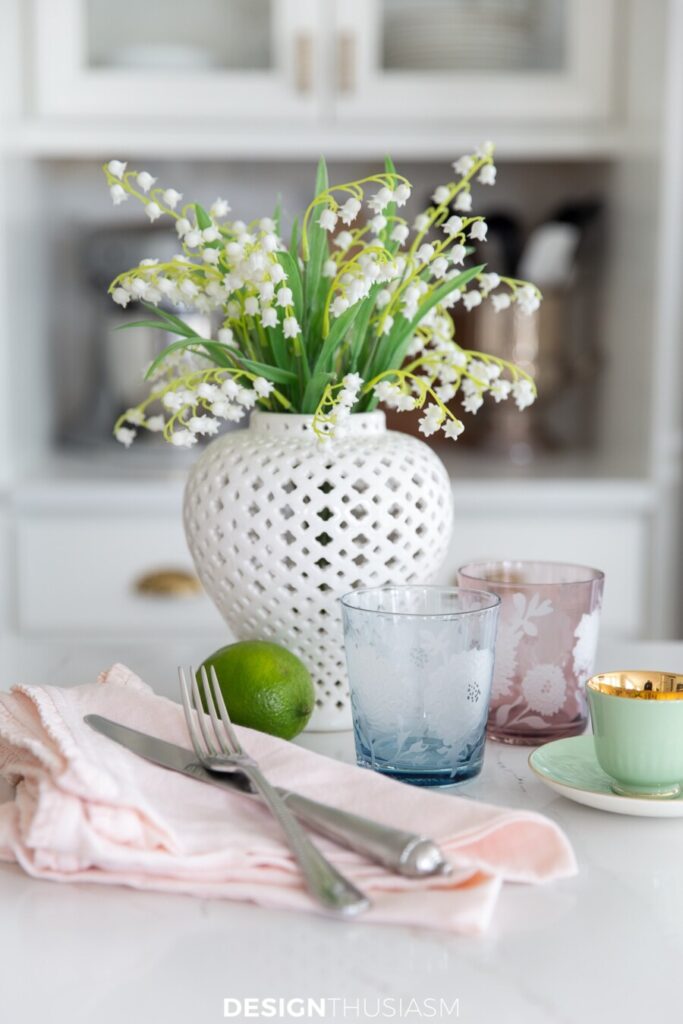 white vase of lilies of the valley and colorful dishes