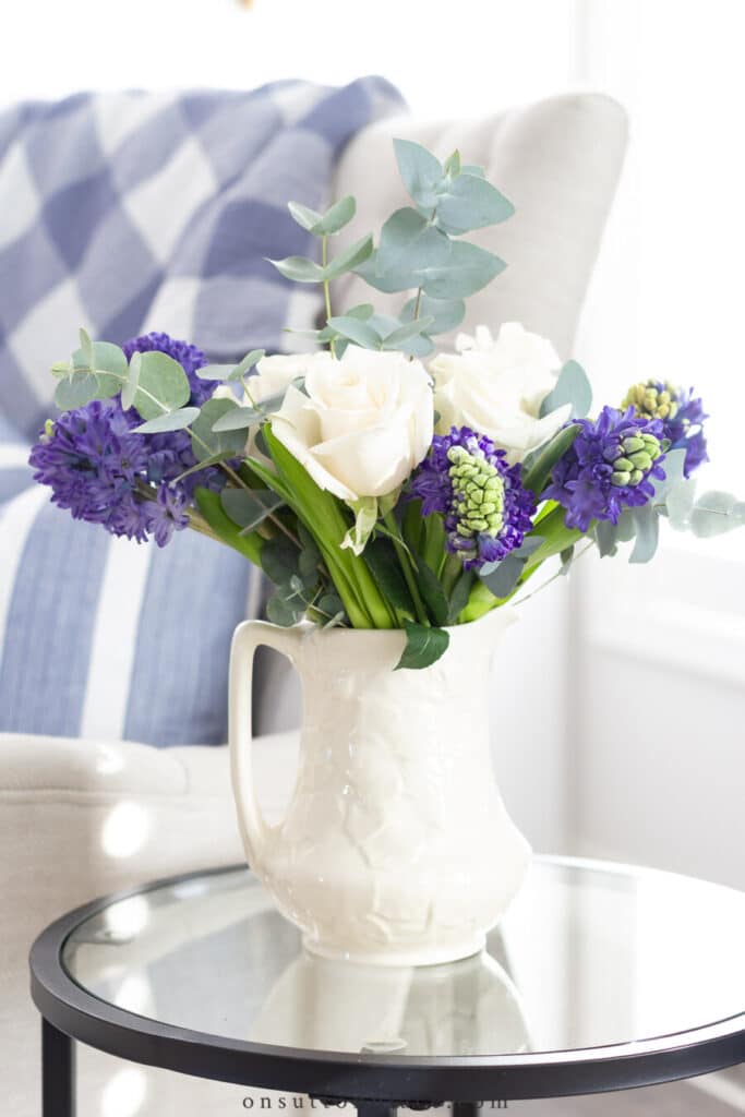 white pitcher filled with purple, green and white flowers
