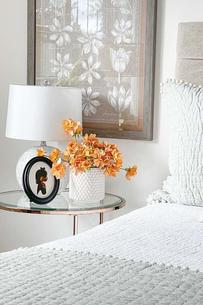 faux flowers on a nightstand near a bed