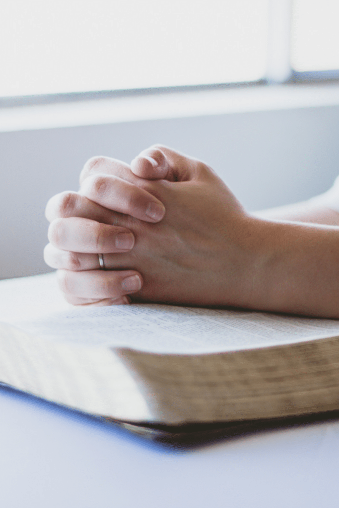 hands in prayer resting on the Bible